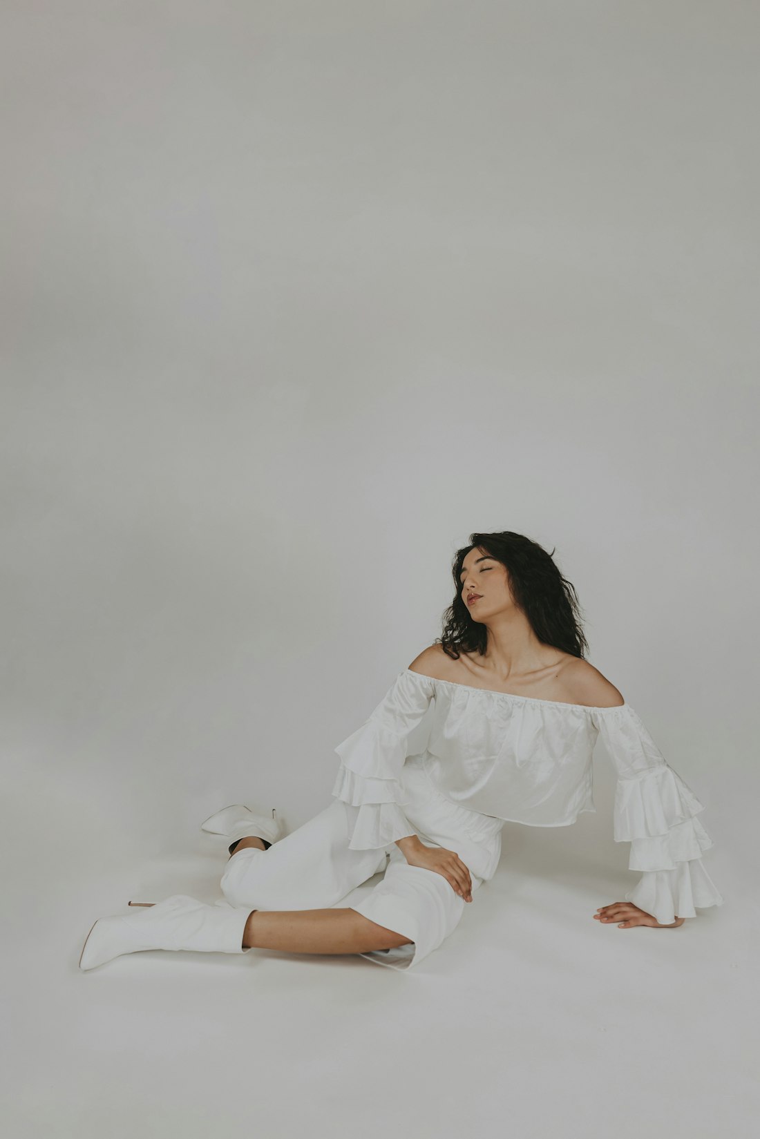 Woman in soft white clothing seated in a bright, airy studio